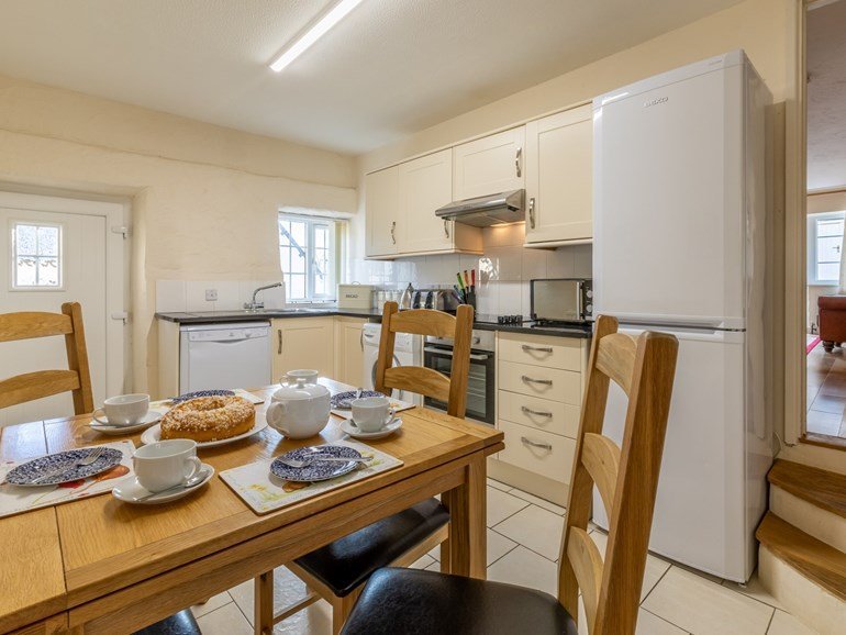 Farmhouse kitchen with oak table laid for tea