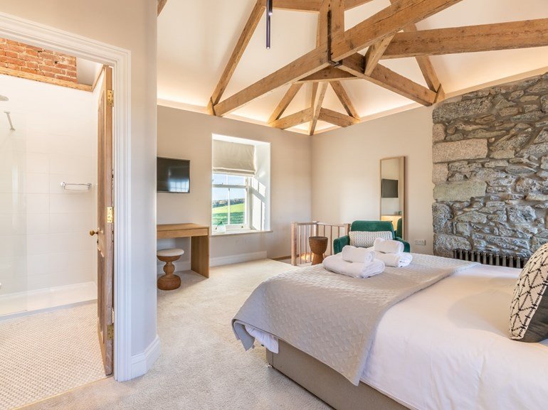 Vaulted bedroom with exposed beams and stone wall