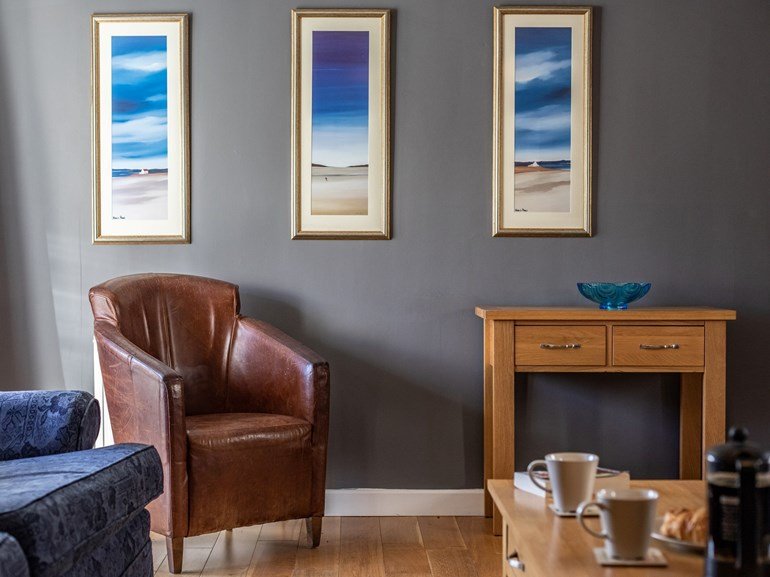 Reading corner with leather armchair and coastal art