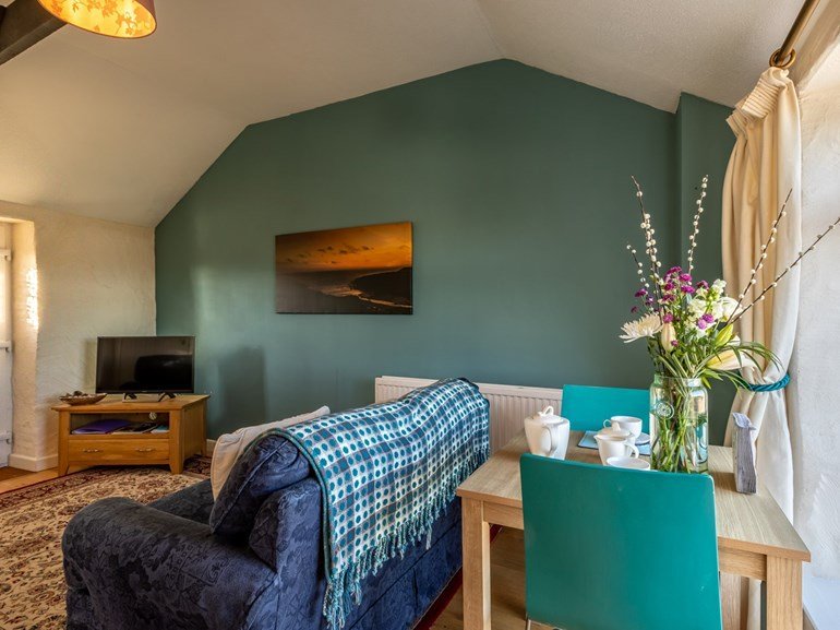 Teal-painted open-plan lounge and diner with fresh flowers